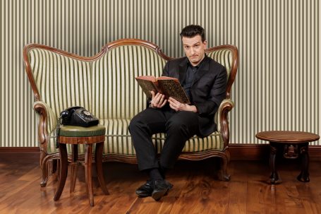 Bild von Stefan Kretschmann, der auf einer gestreiften Couch sitzt.